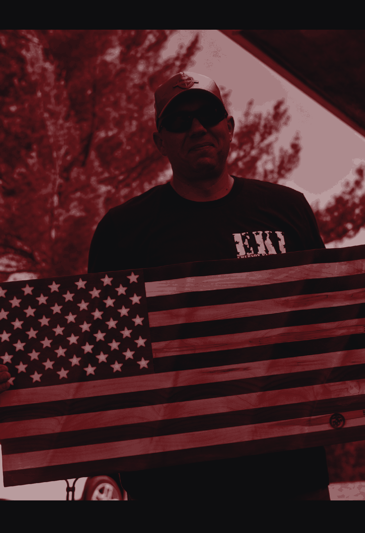 A protector standing watch near an American flag at a Threat Response training camp.
